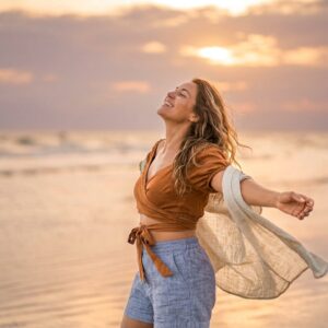 Blije vrouw op het strand tijdens zonsondergang